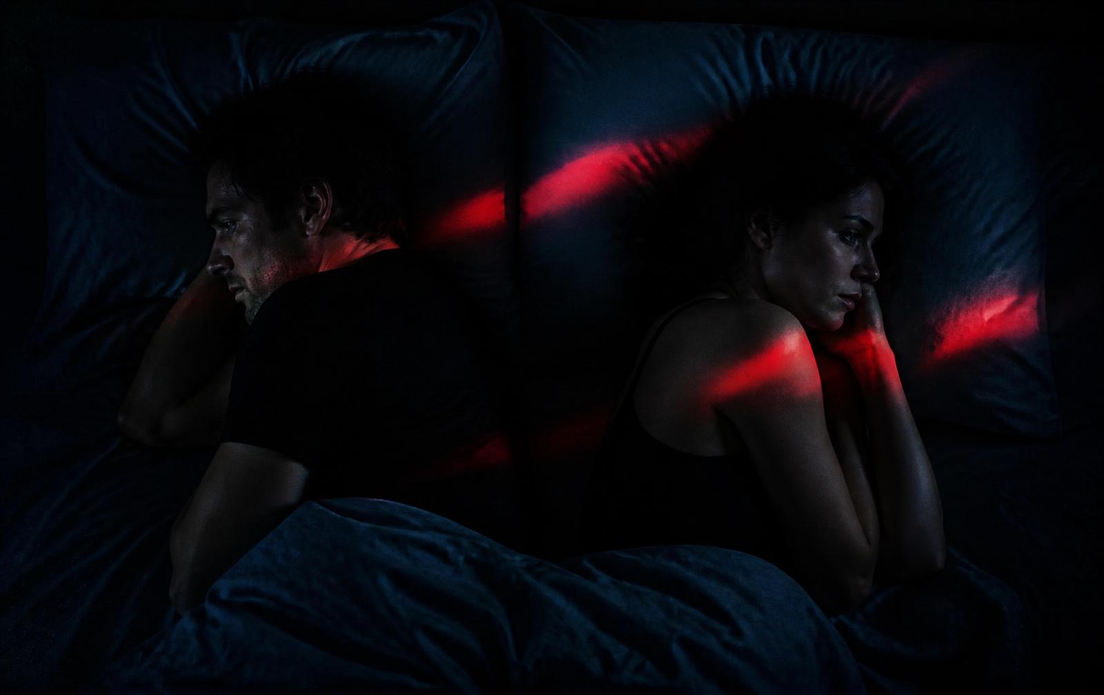 Casal deitado de costas um para o outro na cama, distantes